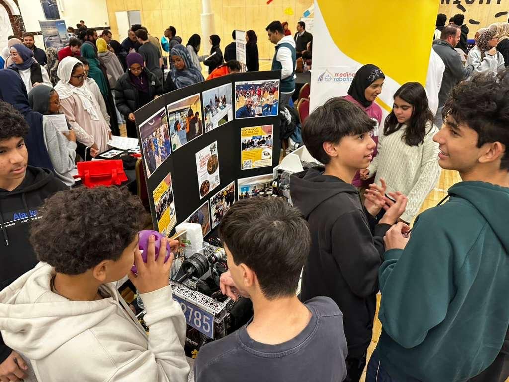 Students around an FTC robot at a busy indoor exhibition