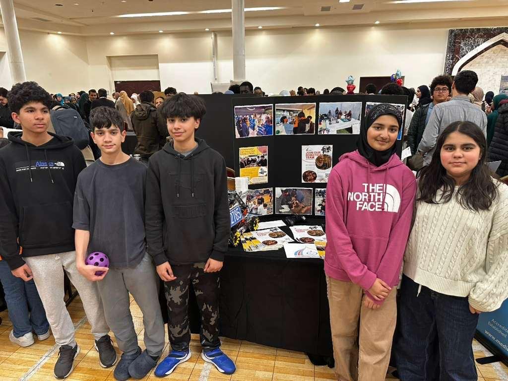 Five Guided Motion students at their robotics exhibition table