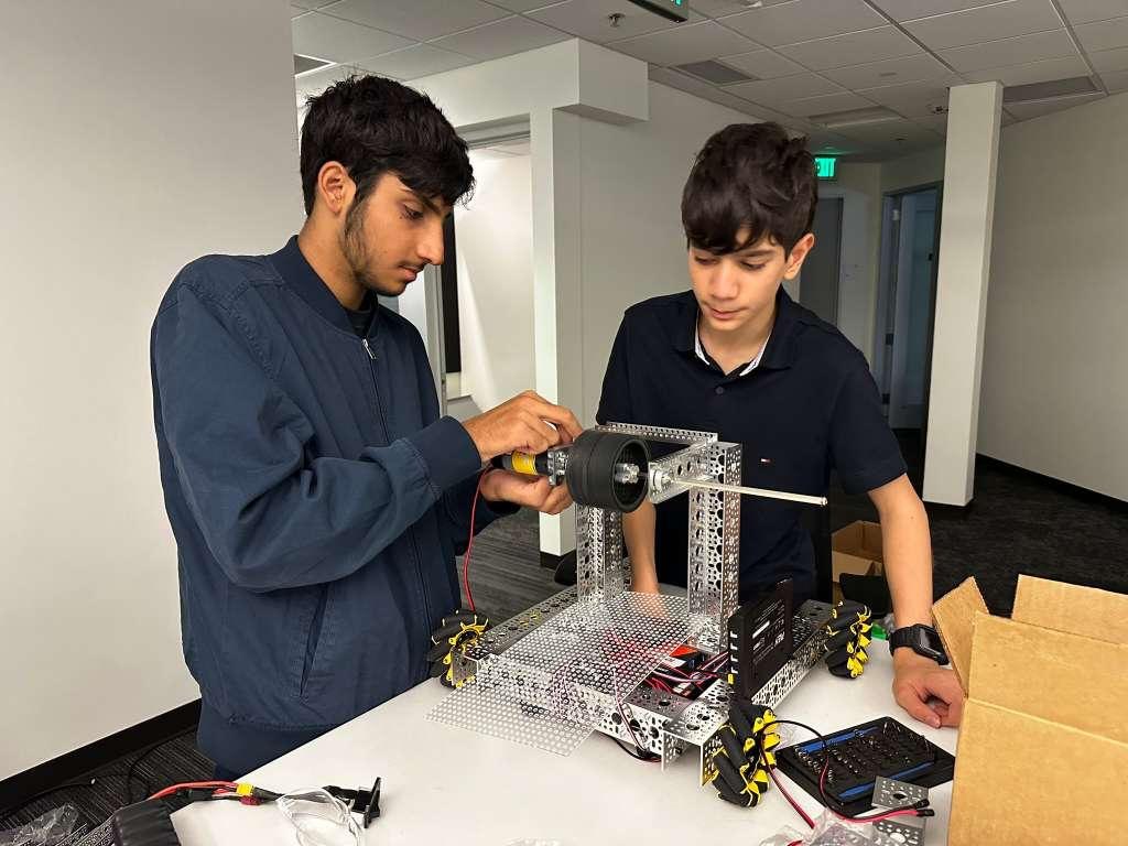 Two students assembling a mecanum drivetrain