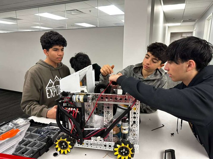 Students wiring the DECODE robot at a white work table