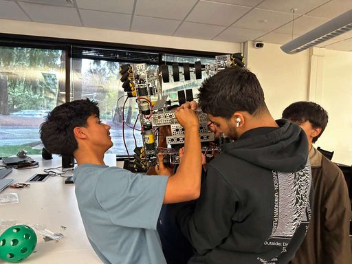 Students working on a robot lift during a shop night