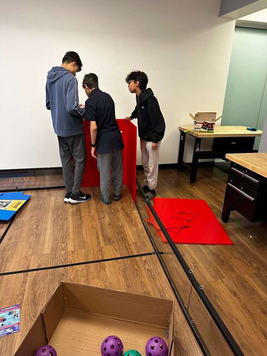 Students at a DECODE practice field with purple game pieces